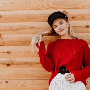 beautiful-blonde-playing-with-her-hair-near-wooden-house-charming-girl-enjoying-warm-autumn-day-outside
